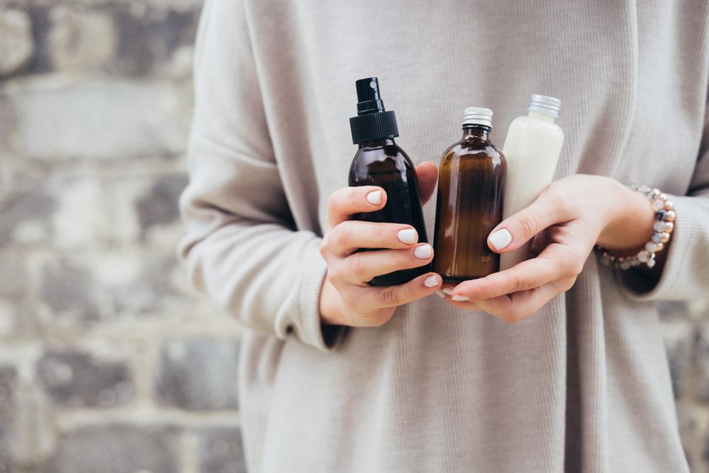 Woman in beige long sleeve shirt holding brown glass bottles