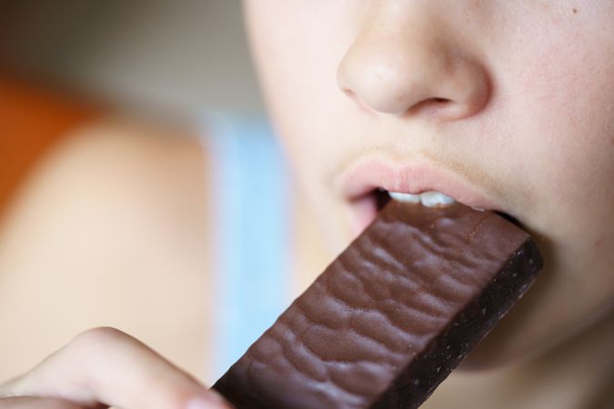 Girl biting into chocolate bar
