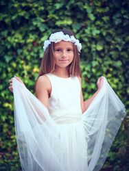 Charming girl in white dress and floral wreath against green bus