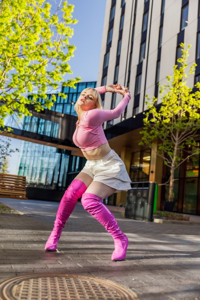 Fashionable Young Woman Wearing Pink Outfit And Voguing On City Street