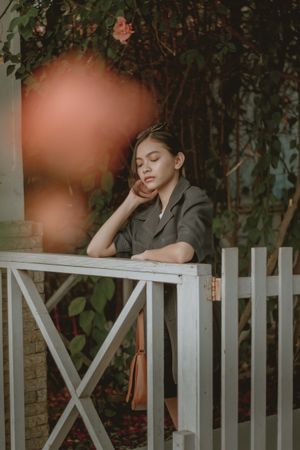 Teenage girl standing beside wooden rail in a garden