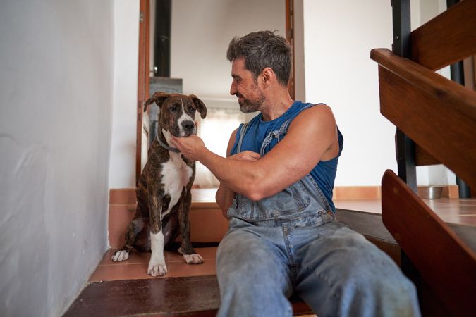 Happy man playing with dog at home