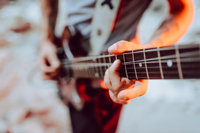 Man clamping strings on guitar neck