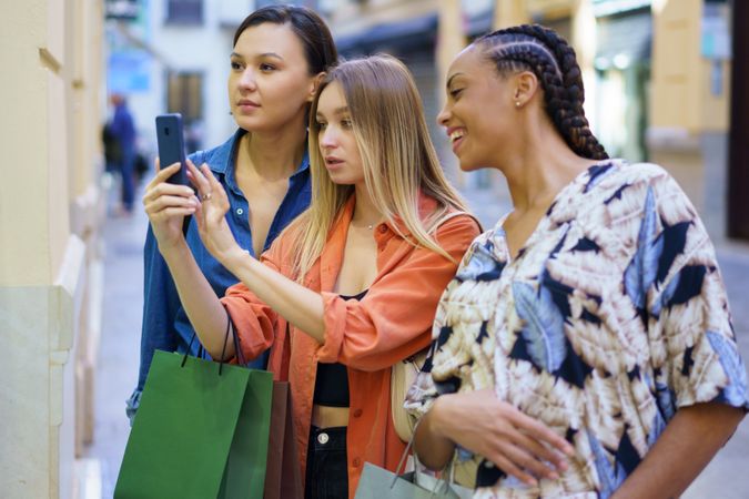 Women on shopping trip taking picture of storefront