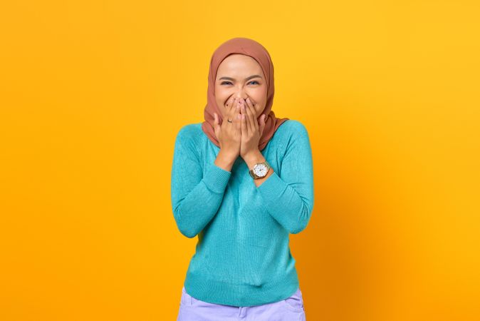 Muslim woman pleasantly surprised and covering mouth