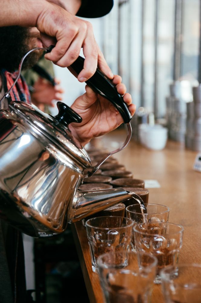 Close up, cropped shot of man pouring hot water into glasses