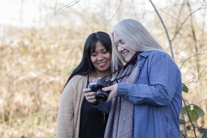 Two happy women review images from a photoshoot outdoors.