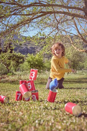Boy playing with knock down cans in park