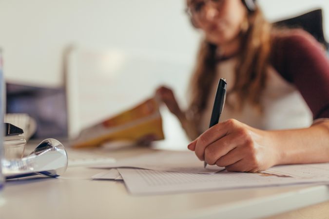 Woman writing notes on paper while working at tech startup