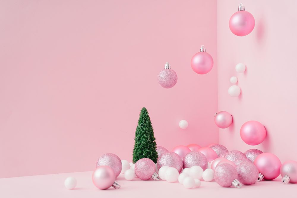 Baubles in a variety of pink shades in corner of pink room with Christmas tree