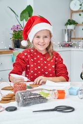 Content girl applying sweet icing on gingerbread cookie