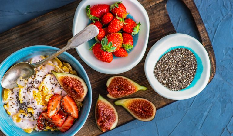 Top view of traditionally healthy breakfast with chia, figs and strawberry on board