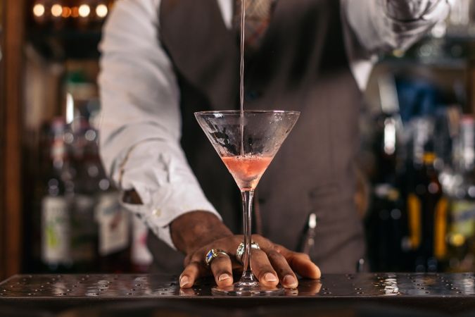 Black bartender preparing a cocktail in a traditional cocktail bar