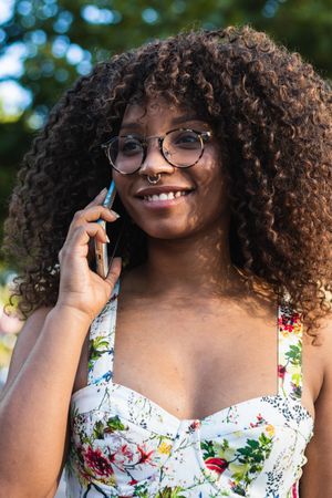 Glad woman speaking on smartphone in park