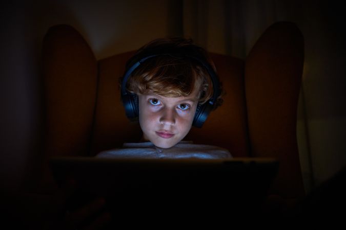 Boy using tablet in dark living room