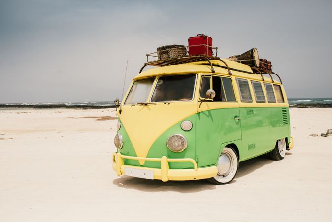 Colorful minibus with trailer parked on sandy shore in sunny day