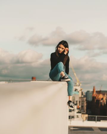 Girl sitting on  concrete wall on a rooftop