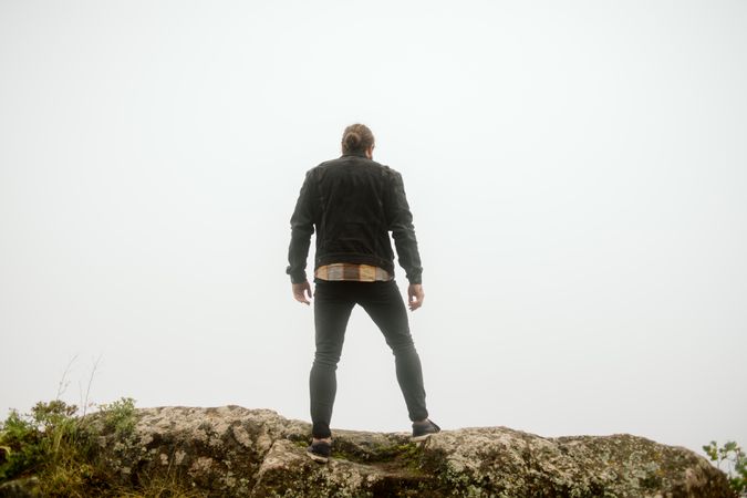 Anonymous man standing on cliff near countryside road