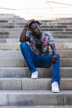 Stylish Black hipster man sitting on stairs in city