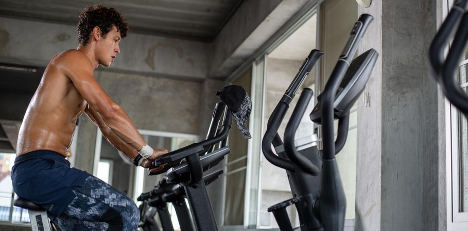 Muscular man working out on cycling machine at the gym