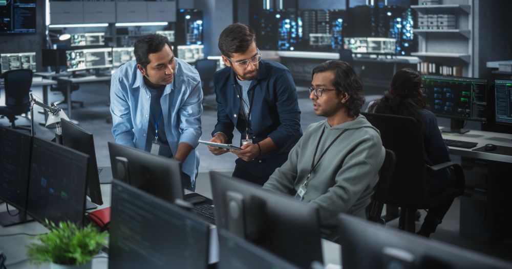 Team of Three Multiethnic Diverse Software Developers Talk, Discuss and Collaborate on an AI Project.