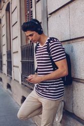 Young man with headphones and smartphone walking outdoors