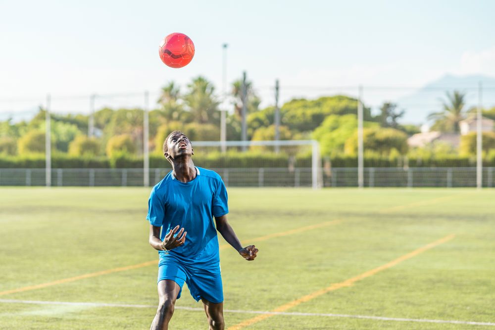 Black teenager jugging football ball on head