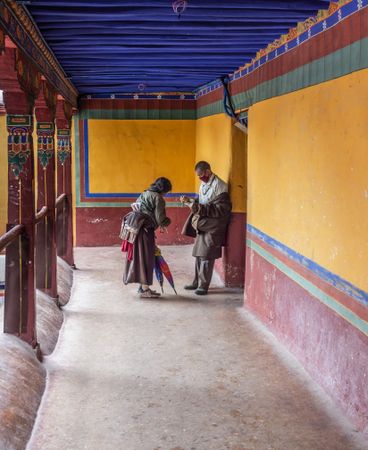 Tibet - August, 29 2014: Woman talking to monk in corridor
