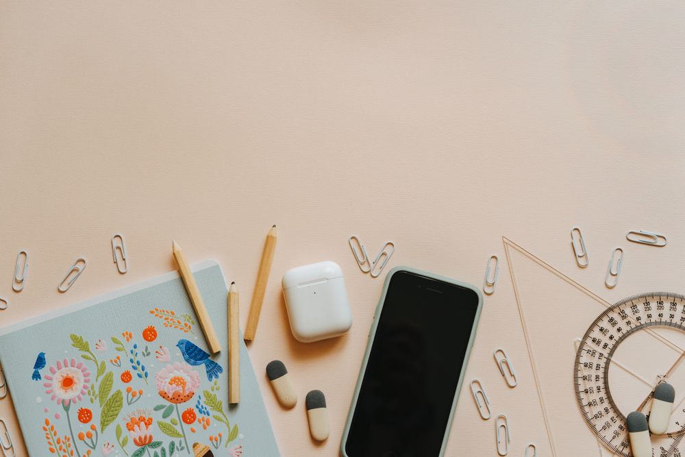 Top view of smartphone and stationary on pink surface