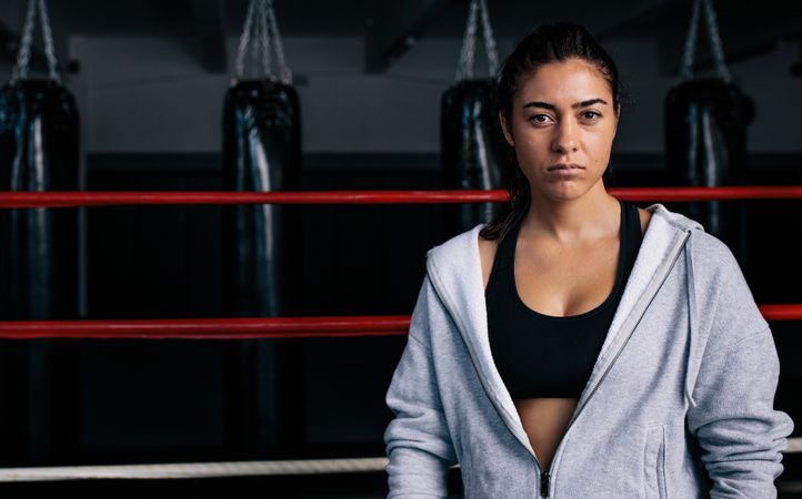 Portrait of female boxer standing in the ring in hoodie