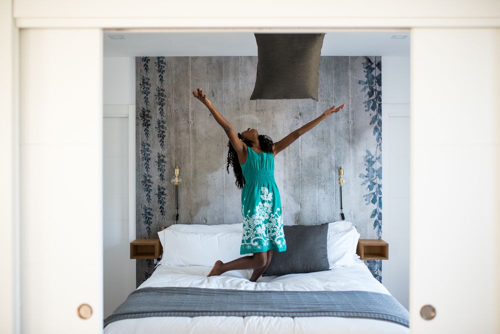 Black girl with headphones dancing on bed