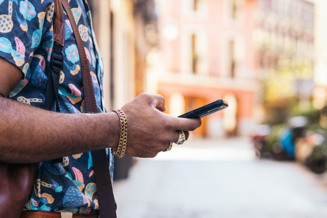 Stylish Black man using smartphone outdoors in the city