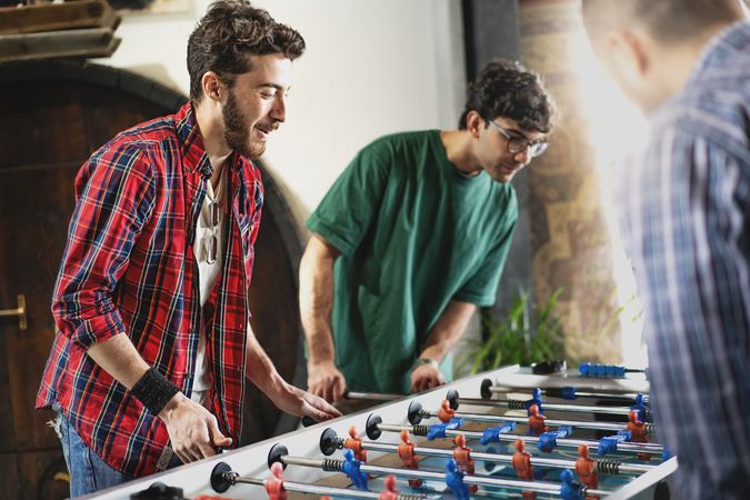 Group of cheerful young people friends playing table football together