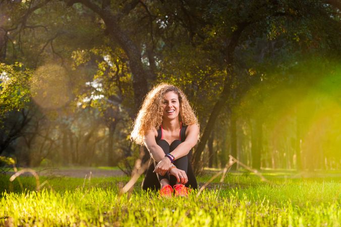 Happy woman sitting on sunny lawn