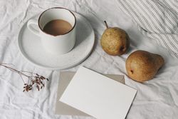 Blank business card mockup and pear fruit on bed sheets