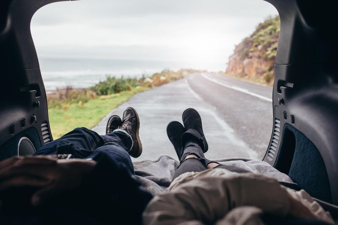 Man and woman relaxing in the car trunk along the road