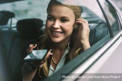 Happy young businesswoman talking on the mobile phone while sitting on back seat of a car 4md2z5