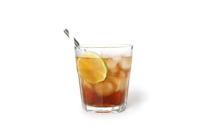 Glass of cold cola with lime isolated on blank background