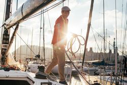 Sunset photo of captain of yacht collecting the ropes