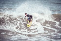 Male surfer on surfboard riding on wave in stormy sea