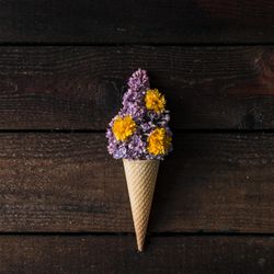 Ice cream cone with purple lilac on wooden background
