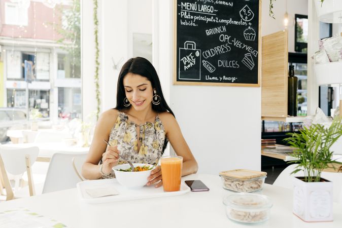 Cheerful woman with healthy food in cafe