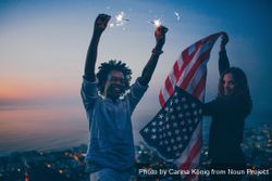 Smiling couple with sparklers and the American flag at dusk PbYqDb