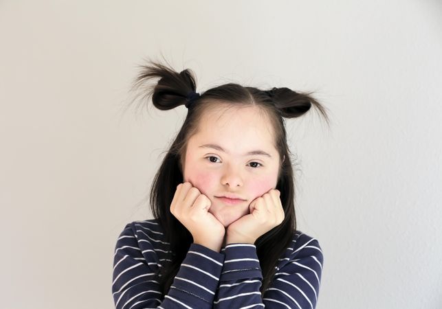 Portrait of young child holding her hands to her chin