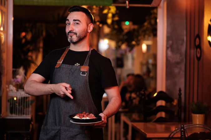 Cheerful waiter serving snack in restaurant