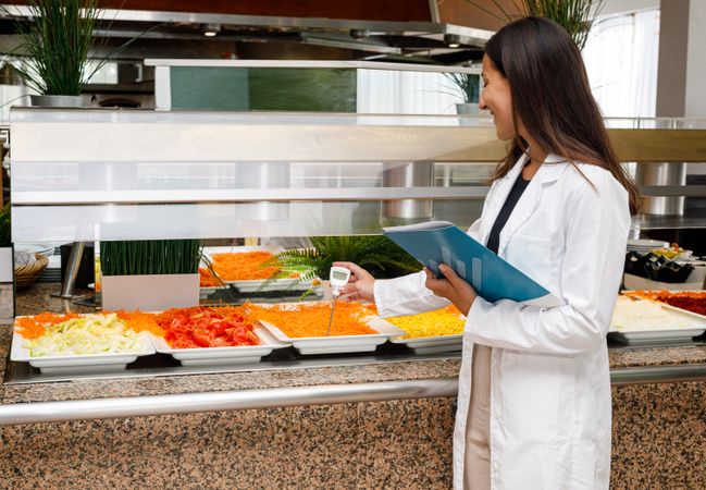 Adult employee checking food quality in canteen
