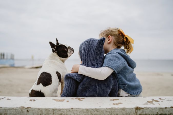 Kids hugging dog on beach