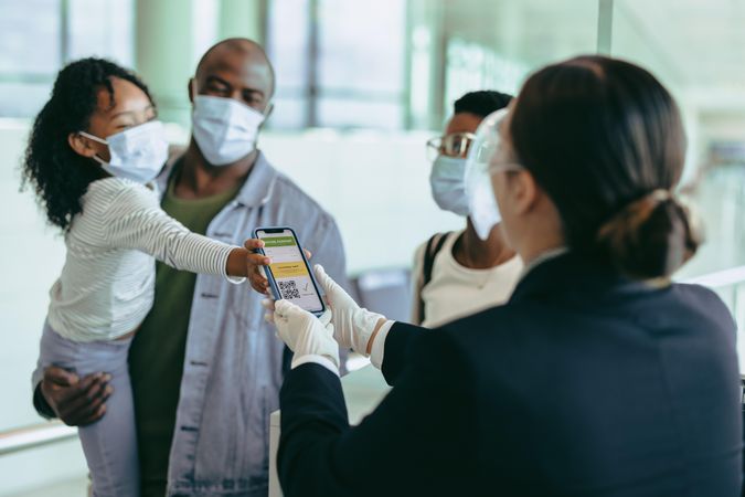Girl with family during pandemic showing vaccine passport to airport staff
