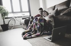 Couple wrapped in plaid watching laptop