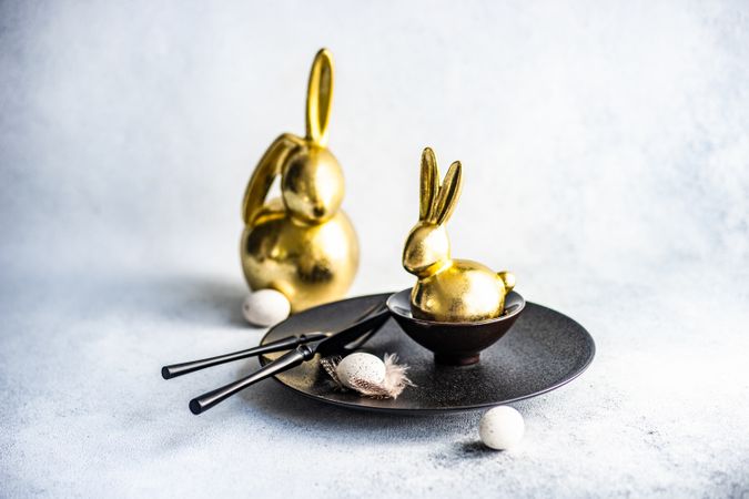 Easter holiday card concept with golden figurines on table setting